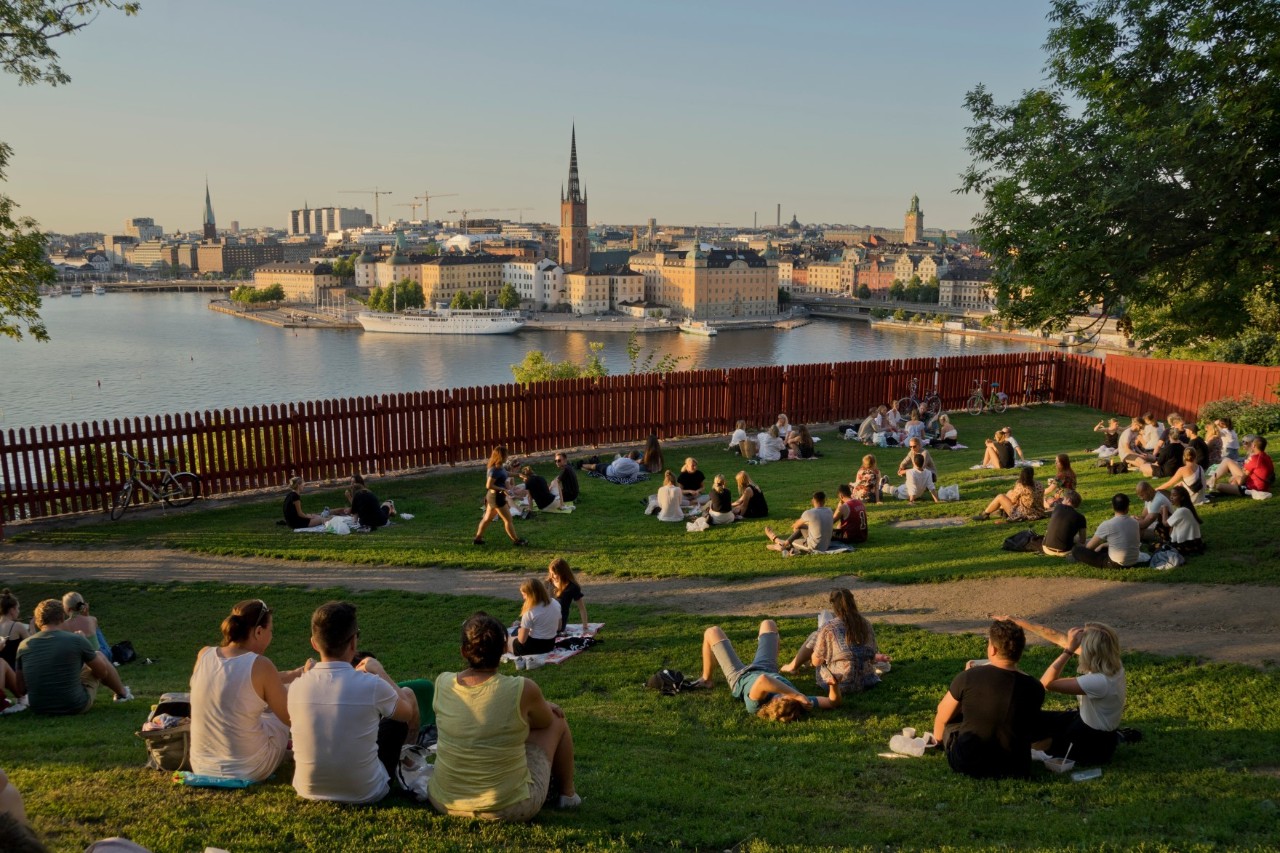 Menschen sitzen im Park und blicken auf Gamla Stan.