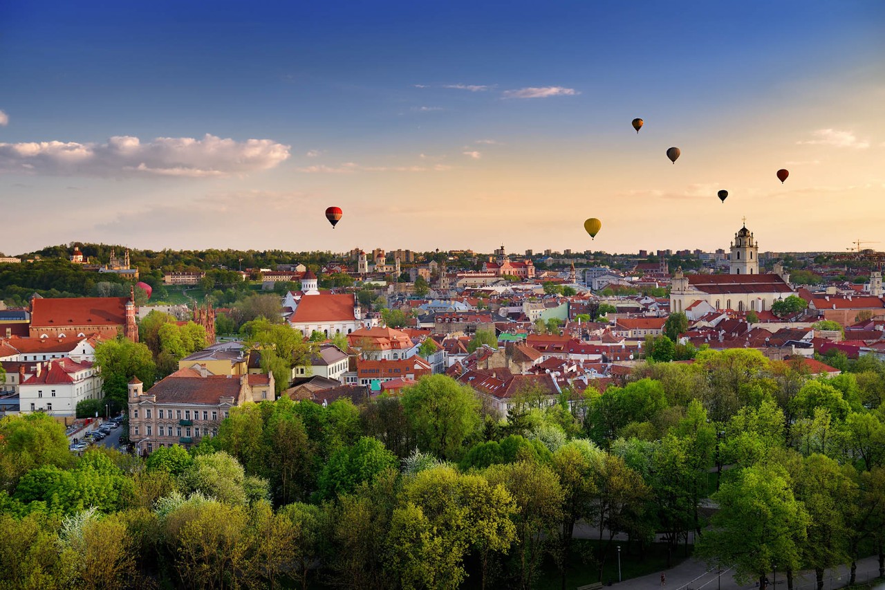 Altstadt von Vilna im Abendlicht mit bunten Heißluftballons am Himmel.