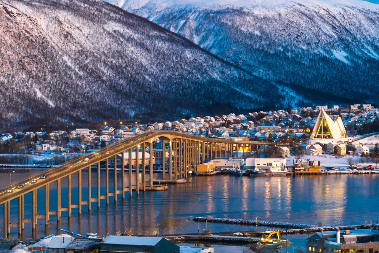 Tromsø-Brücke mit verschneiten Bergen und Eismeerkathedrale im Hintergrund.