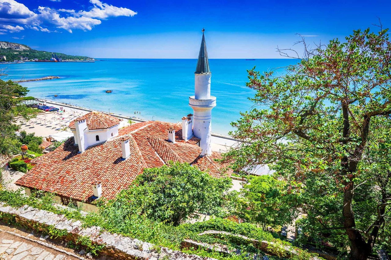 Schloss Balchik mit Turm, umgeben von Gärten und Blick aufs Meer.