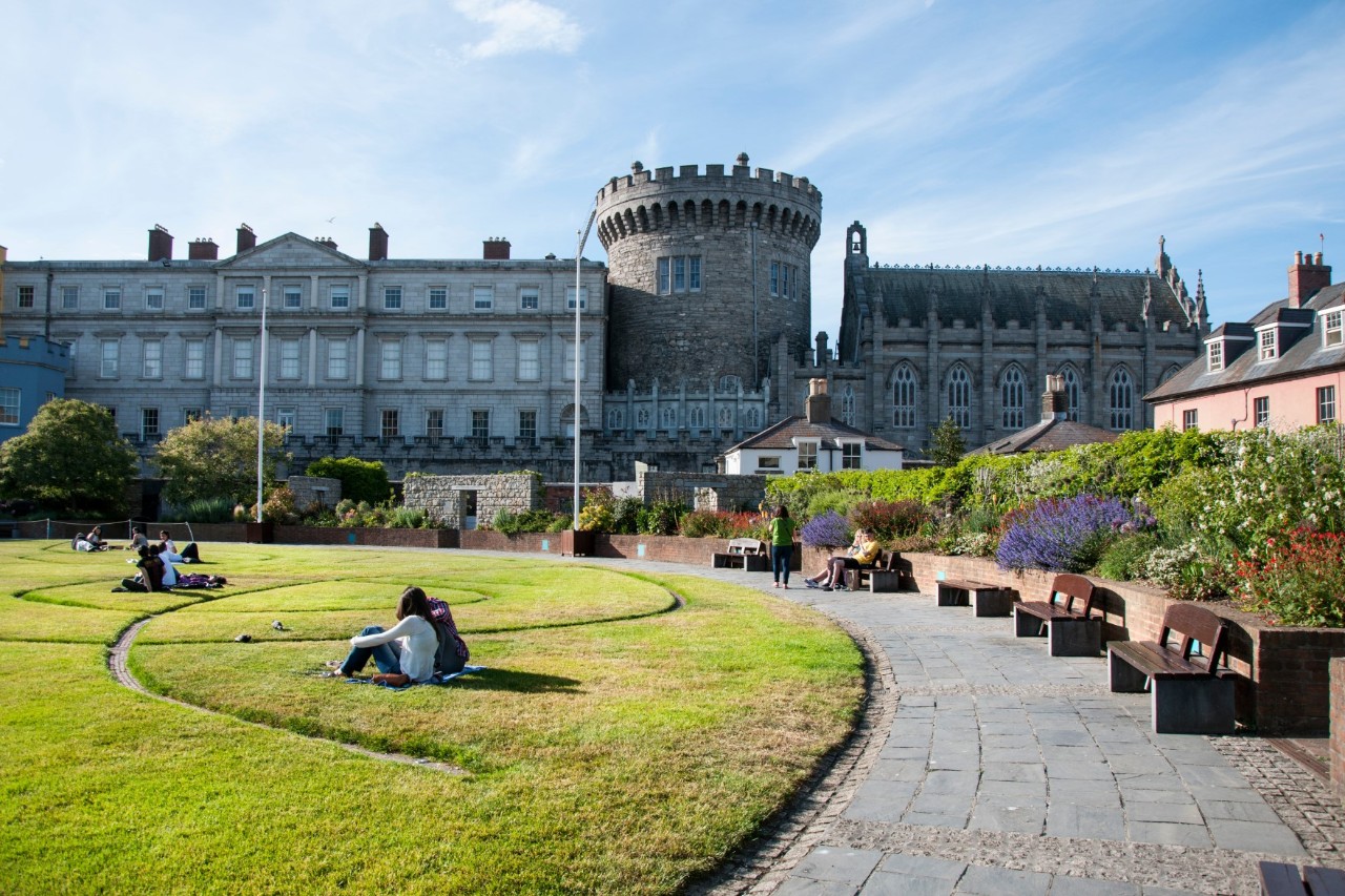 Grünfläche mit Bänken vor dem runden Turm des Dublin Castle.