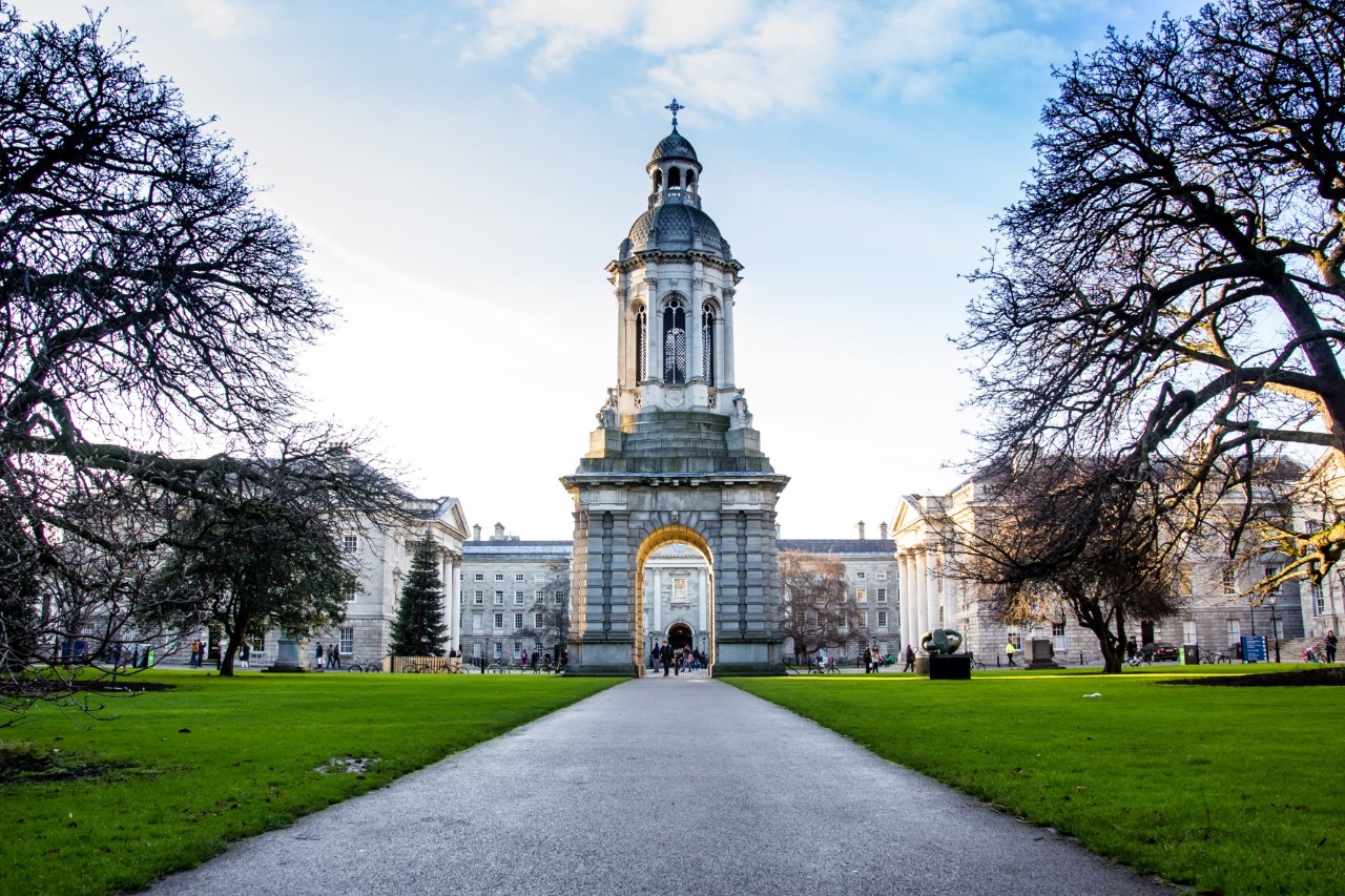 Glockenturm von Trinity College mit Weg und Bäumen.
