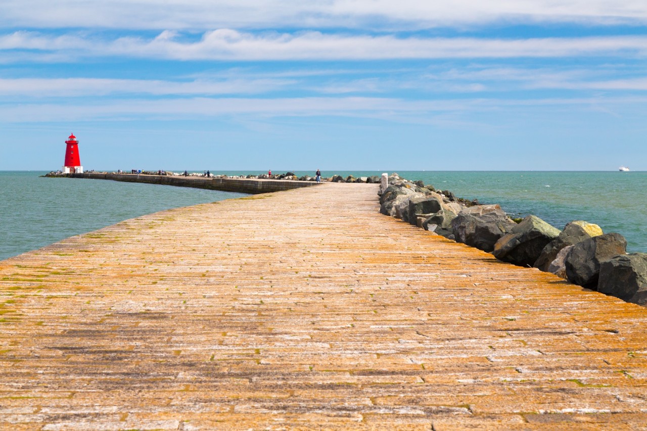 Steinweg zum roten Leuchtturm am Meer.