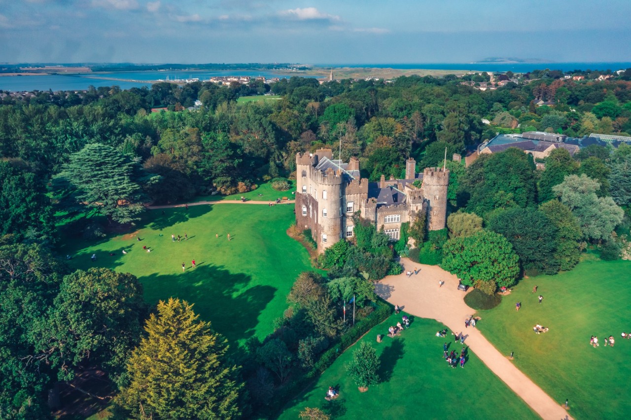 Luftbild von Malahide Castle mit Park und Küste im Hintergrund.