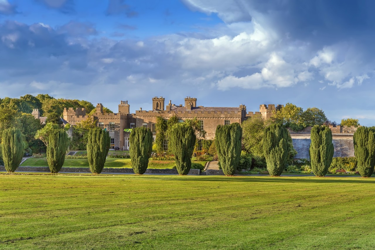 Vorderseite von Malahide Castle mit Zypressen und grünem Rasen.