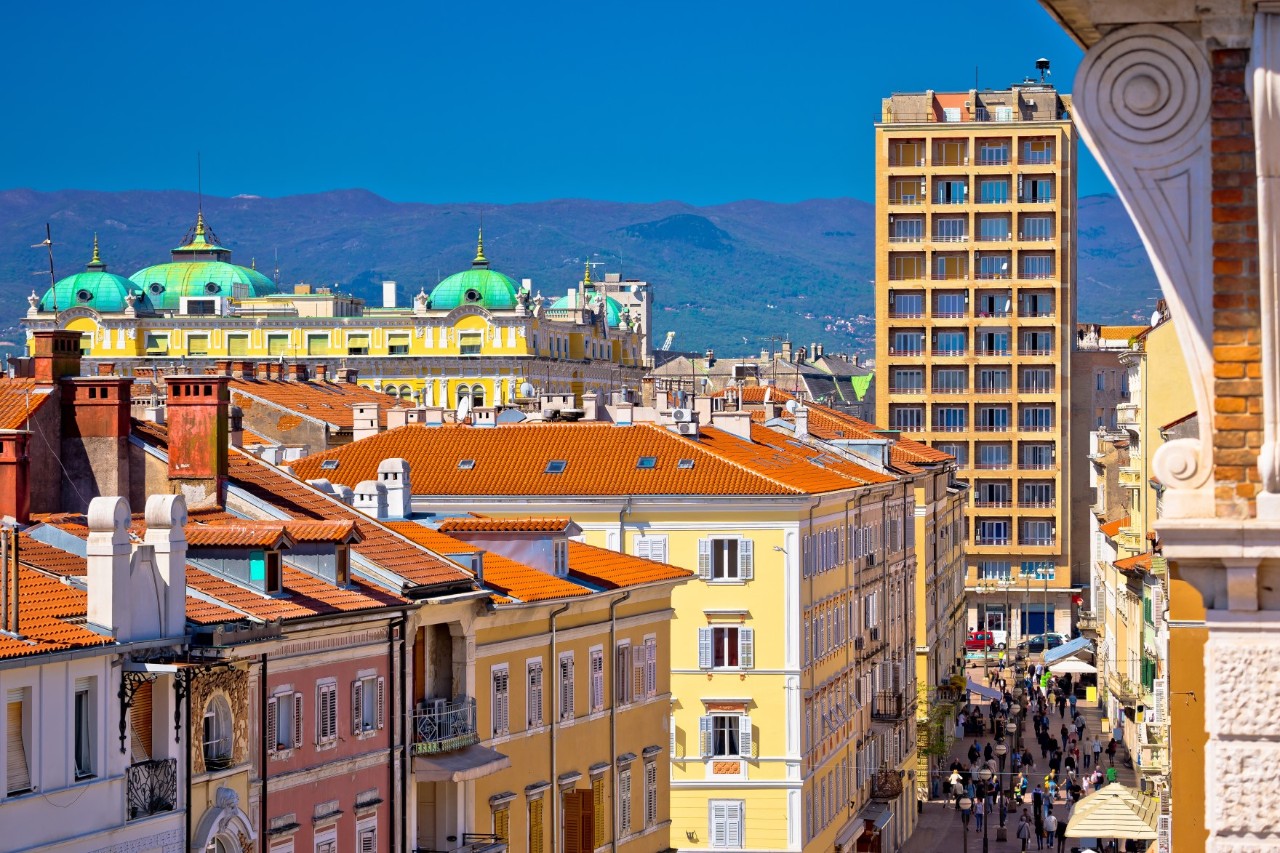 Belebte Innenstadt von Rijeka mit Promenade und historischen Gebäuden.