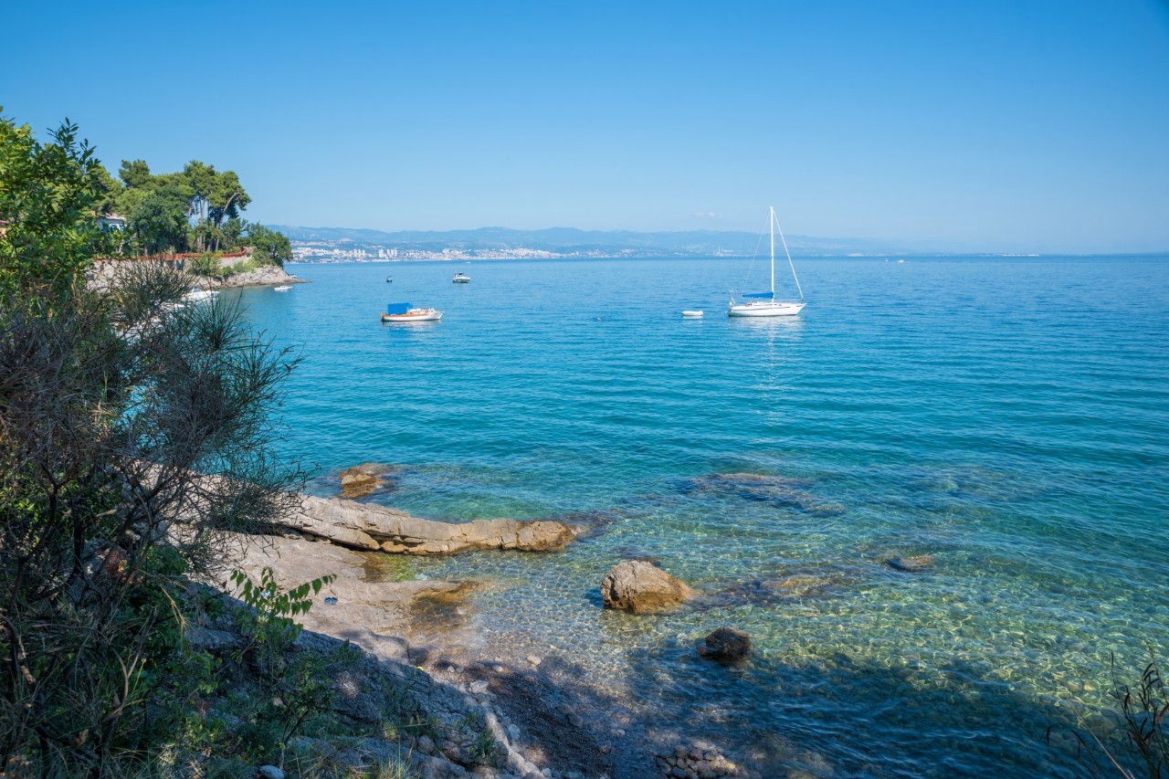 Kiesstrand bei Rijeka mit klarem Wasser, zwei Boote ankern.