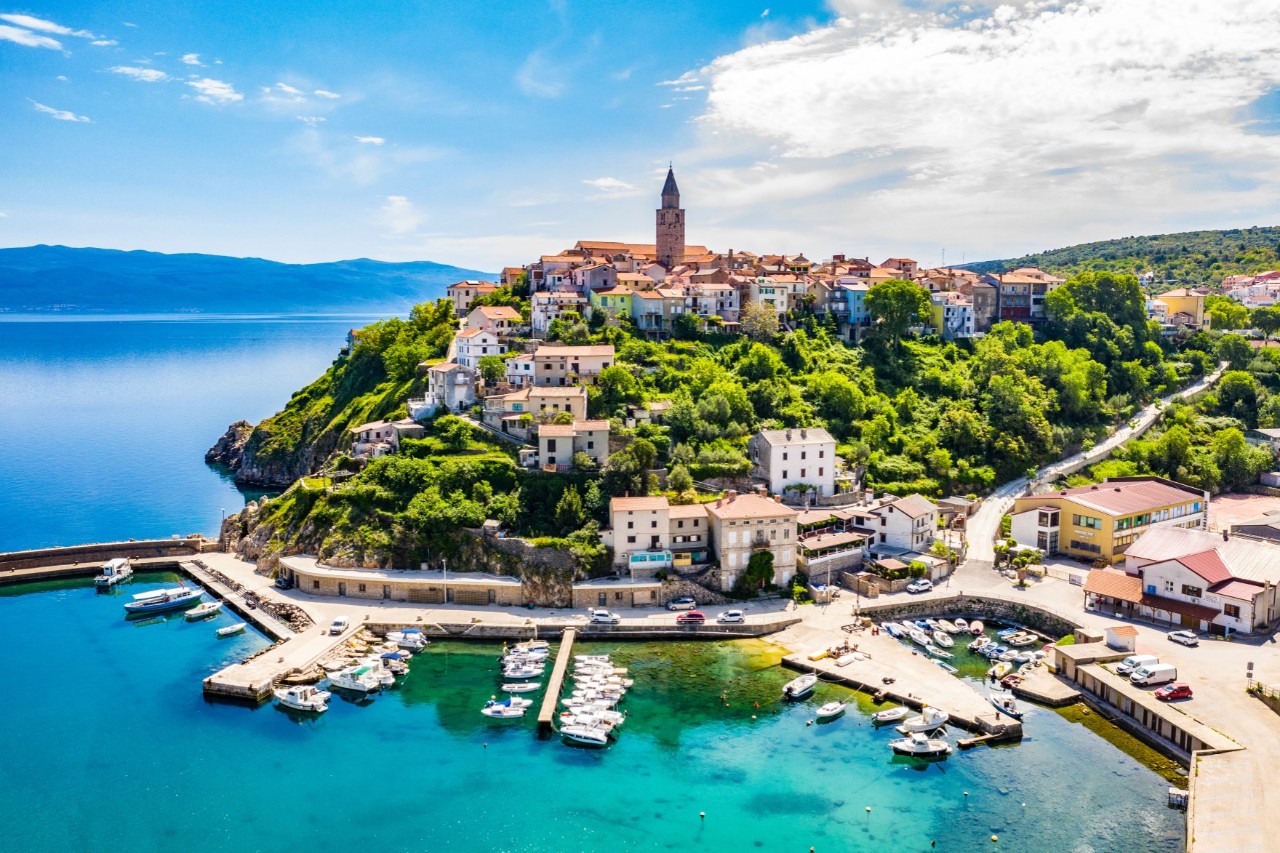 Vrbnik auf Krk mit Häusern auf Klippen über dem Meer und Kirche im Zentrum.