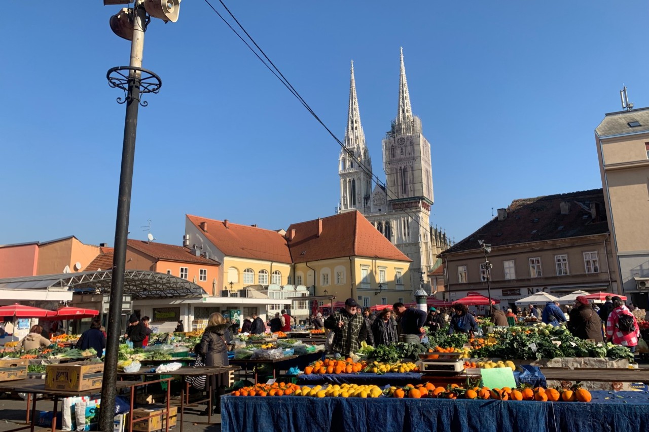 Markstände mit Obst und Gemüse vor der Kathedrale und Häusern 