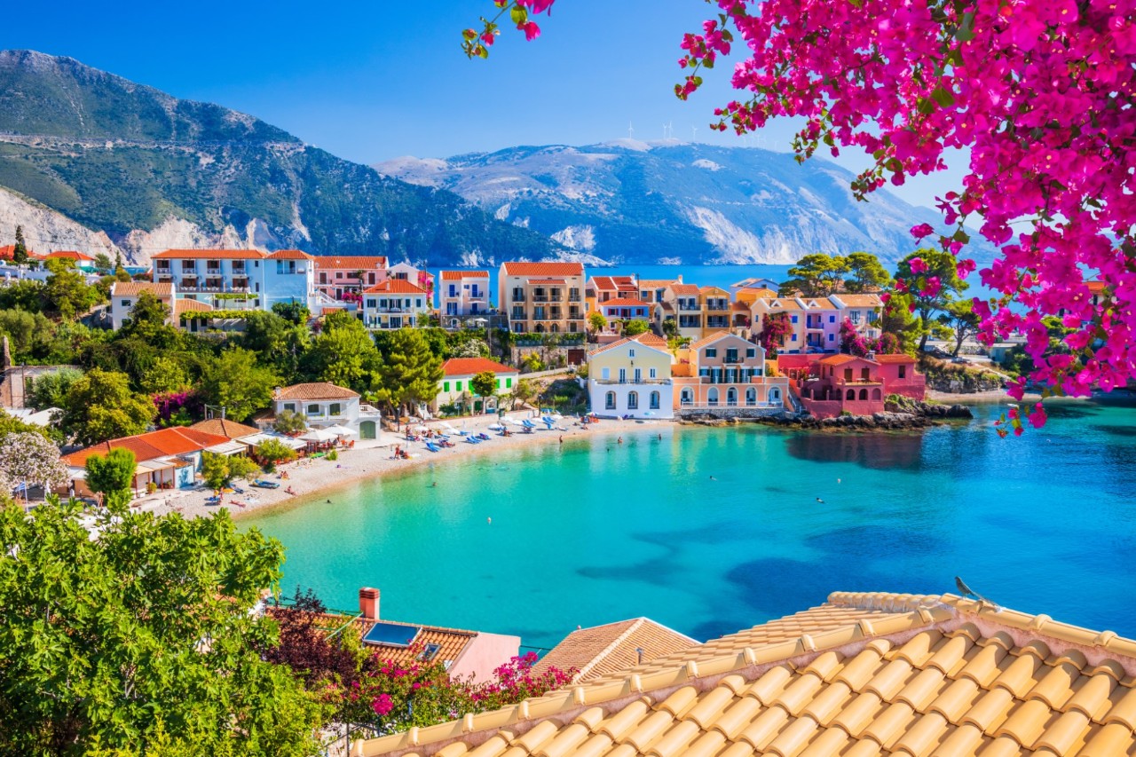 Farbenfrohes Dorf mit Häusern am Meer und blühenden Blumen.