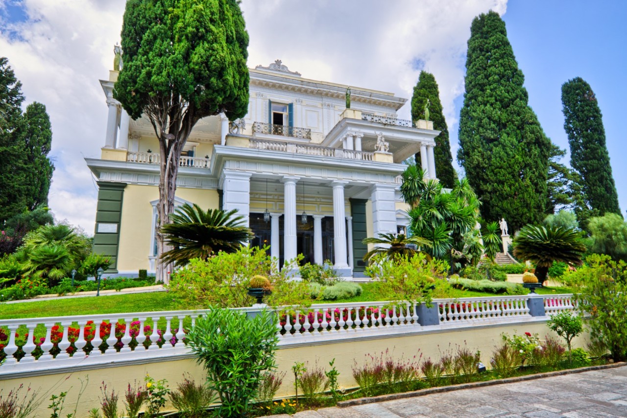 Historische Villa mit Säulenfront und gepflegtem Garten.