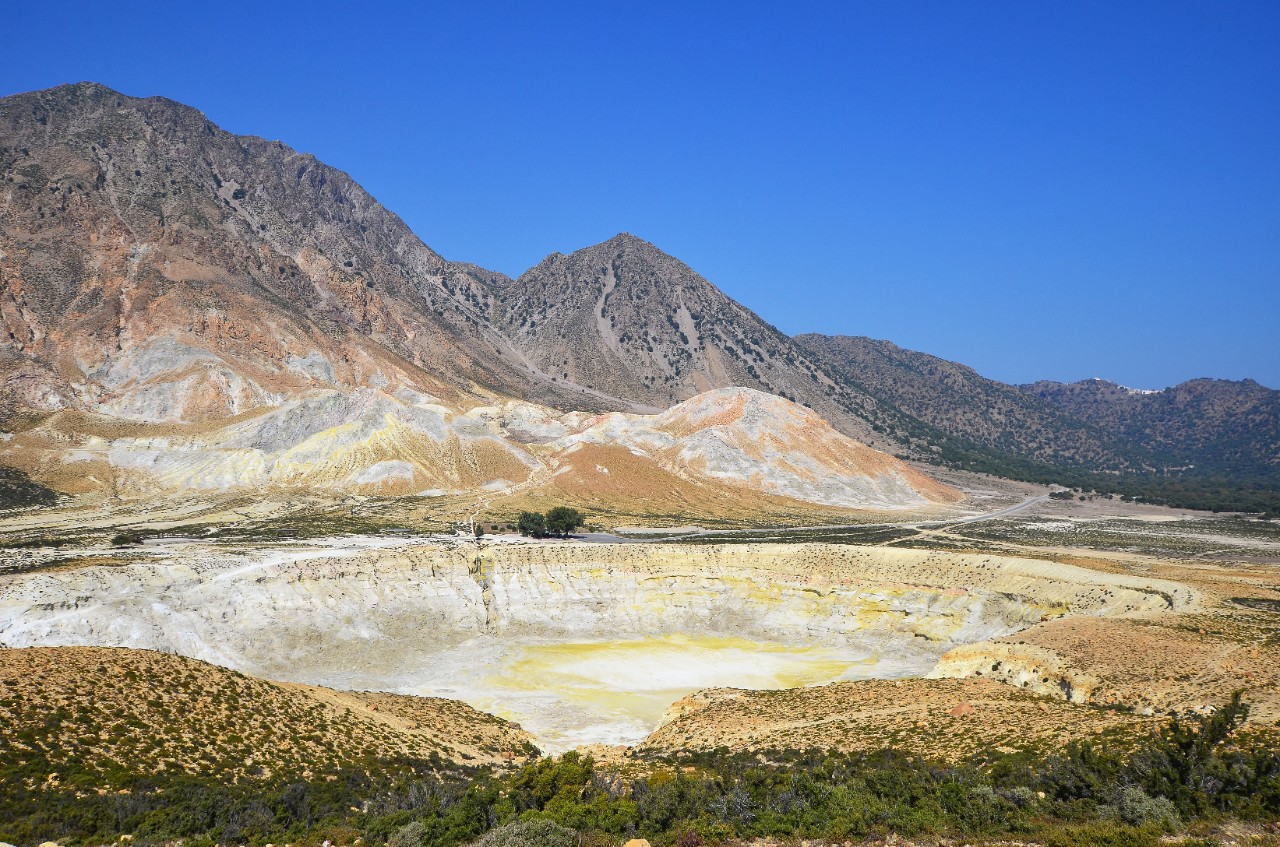 Kraterlandschaft auf der Vulkaninsel Nisyros mit Besuchenden am Rand.