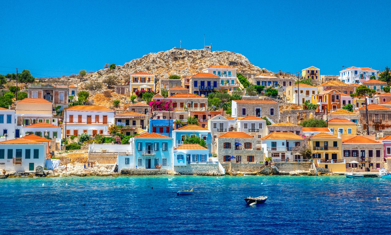 Bunte Häuser direkt am Wasser auf der Insel Halki im Sonnenschein.