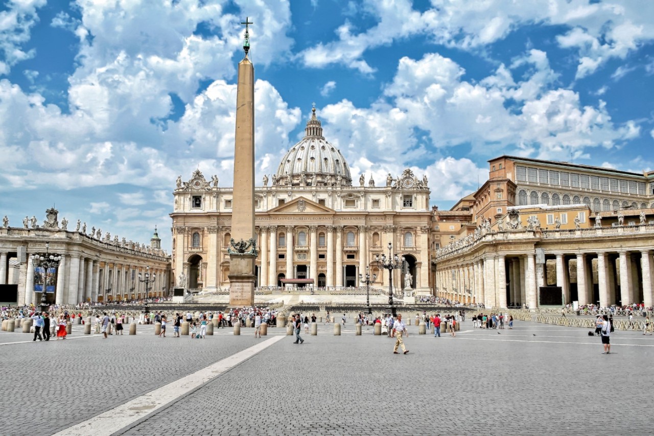 Petersplatz mit Basilika und Obelisk vor blauem Himmel.
