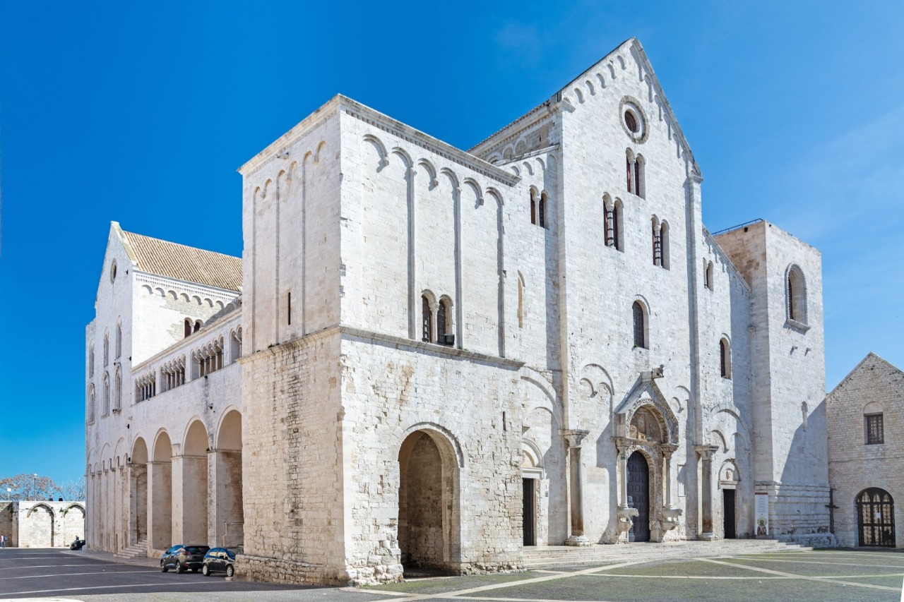 Kirche aus weißgetünchten Steinen im italienischen Stil. Der Himmel ist strahlend blau.