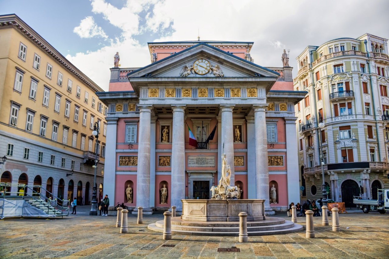 Platz mit drei Gebäuden, in der Mitte das alte Börsengebäude mit vier Säulen und einem Brunnen im Vordergrund.