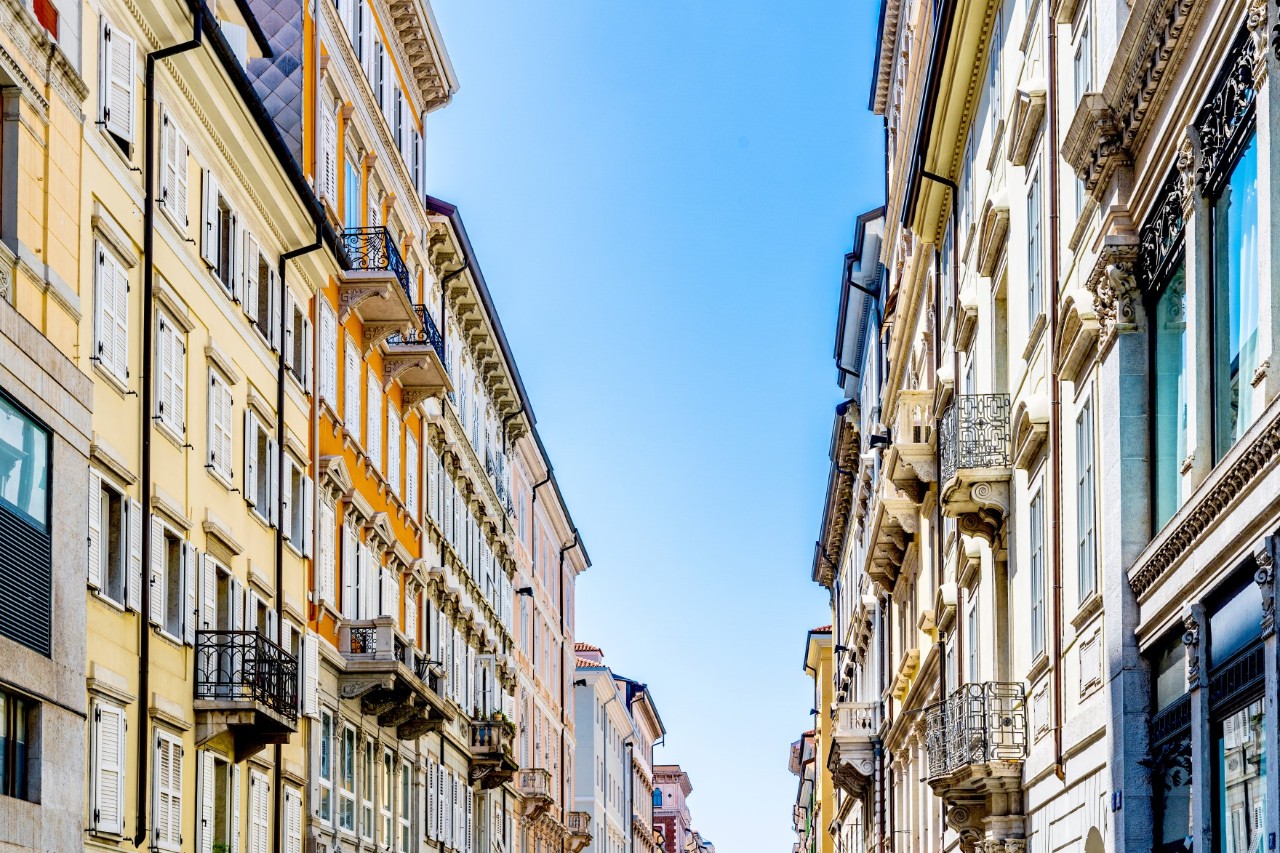 Ansicht der oberen Stockwerke von zwei sich gegenüberliegenden Straßenzügen, dazwischen Himmel. 
