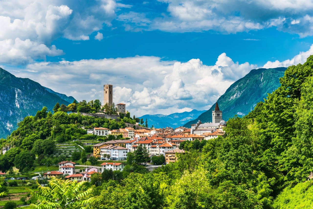 Auf einem Berg gelegenes Dorf mit zwei Kirchtürmen, umgeben von viel Grün.
