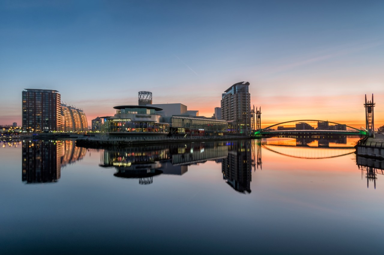 Moderne Gebäude und Brücke am Wasser mit Sonnenuntergang. 