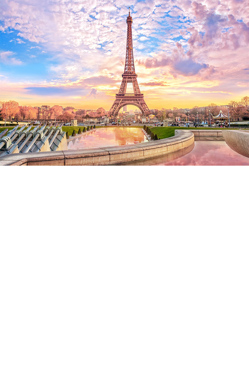 Eiffelturm im Abendlicht mit der Silhouette von Paris im Hintergrund.