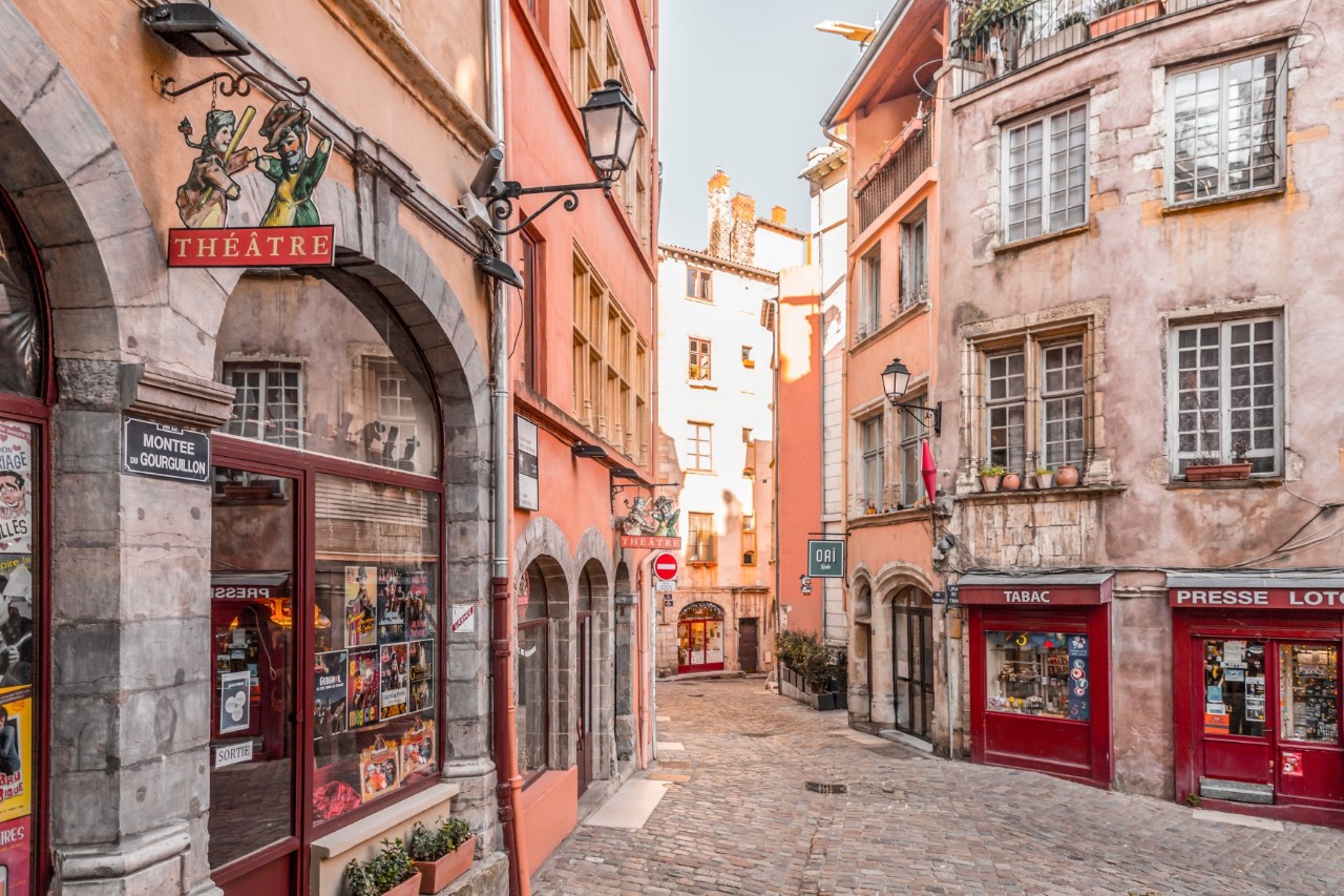 Innenansicht einer engen, charmanten Gasse mit Theater-Schild.