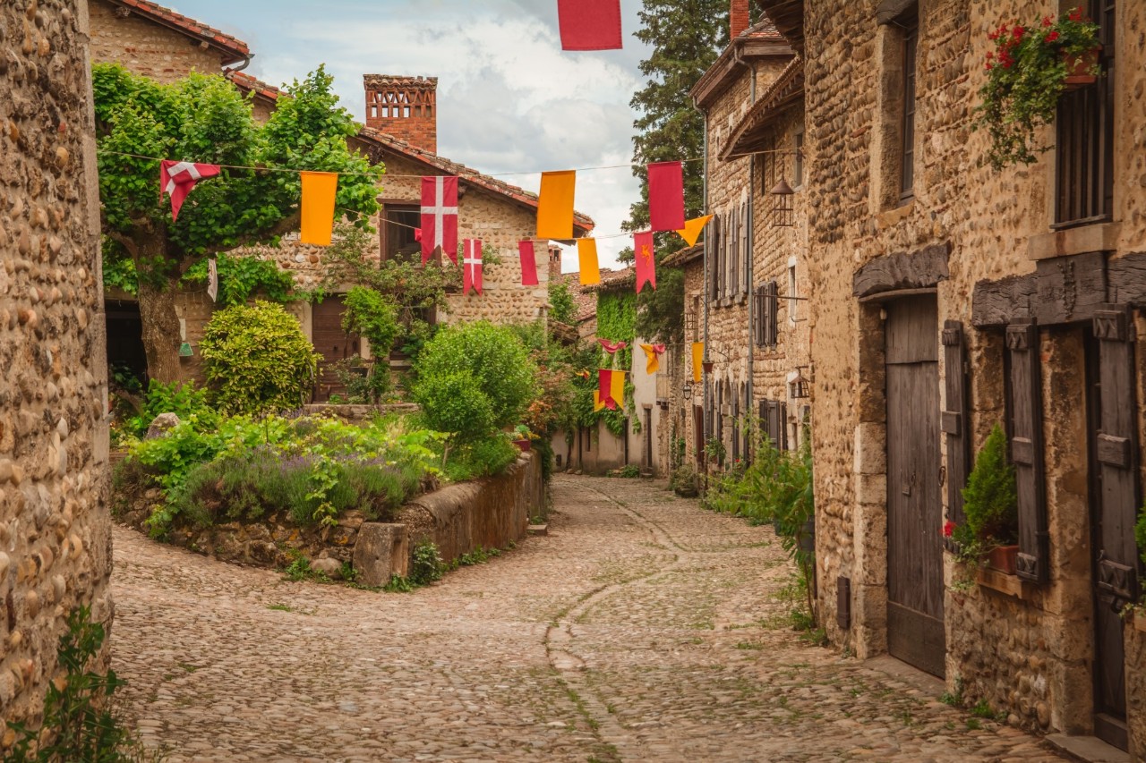 Historische Dorfstraße aus Stein, dekoriert mit bunten Fahnen.