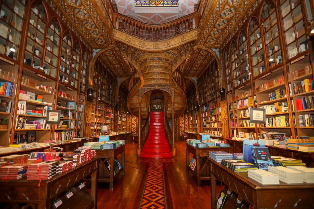 Innenansicht der Livraria Lello mit geschwungener Treppe und verziertem Holz.