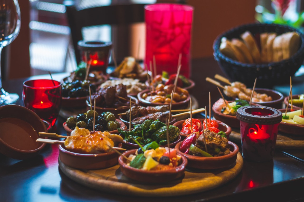 Blick auf bunte Tapas in kleinen Schalen auf Holzteller.