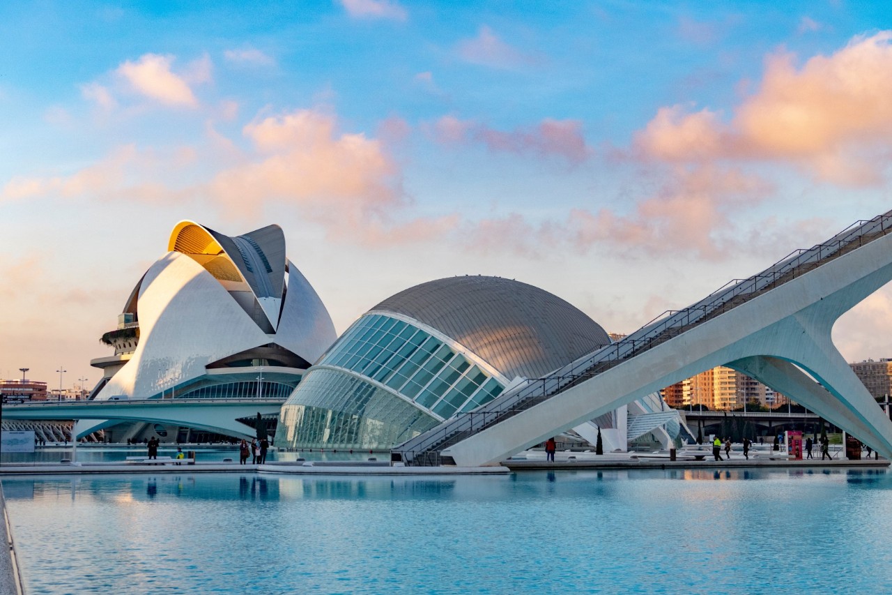 Futuristische, kuppelförmige Gebäude in einem großen Wasserbecken. Die modernen, weißen Strukturen heben sich gegen den Himmel ab.