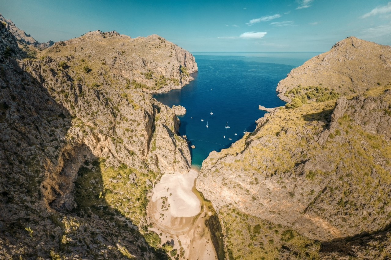 Luftbild der Schlucht Sa Calobra auf Mallorca, das Meer ragt in die Schlucht, darauf sind mehrere Boote zu sehen 