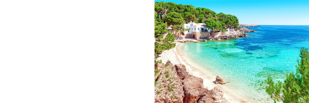 Türkisblaues Wasser und weißer Sandstrand auf Mallorca, eingerahmt von Bäumen und einem weißen Haus