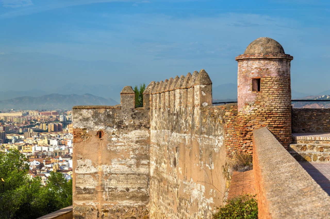 Festung Gibralfaro mit Zinnenmauern und Blick auf das Meer im Hintergrund.
