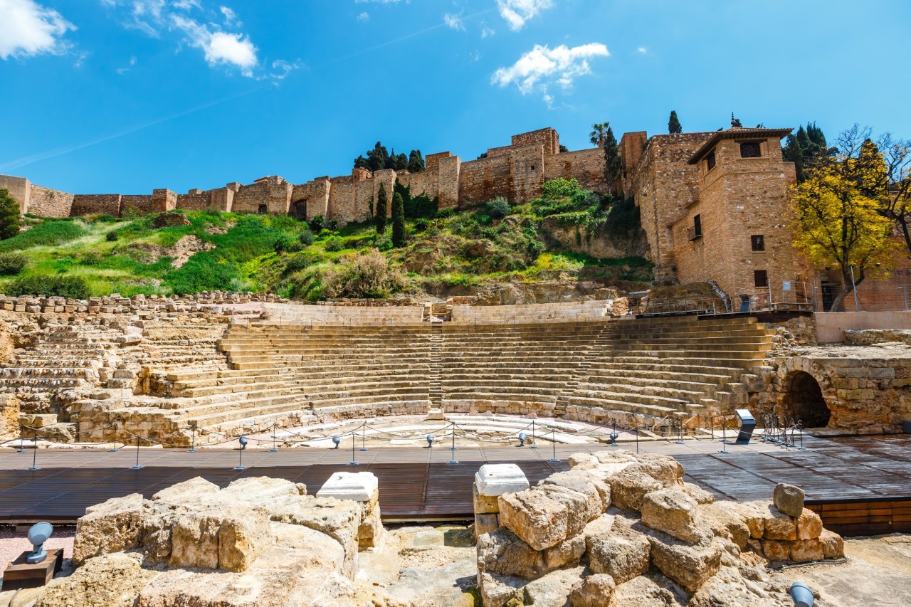 Alte Festung Alcazaba aus Sandstein mit Türmen und Palmen im Vordergrund.