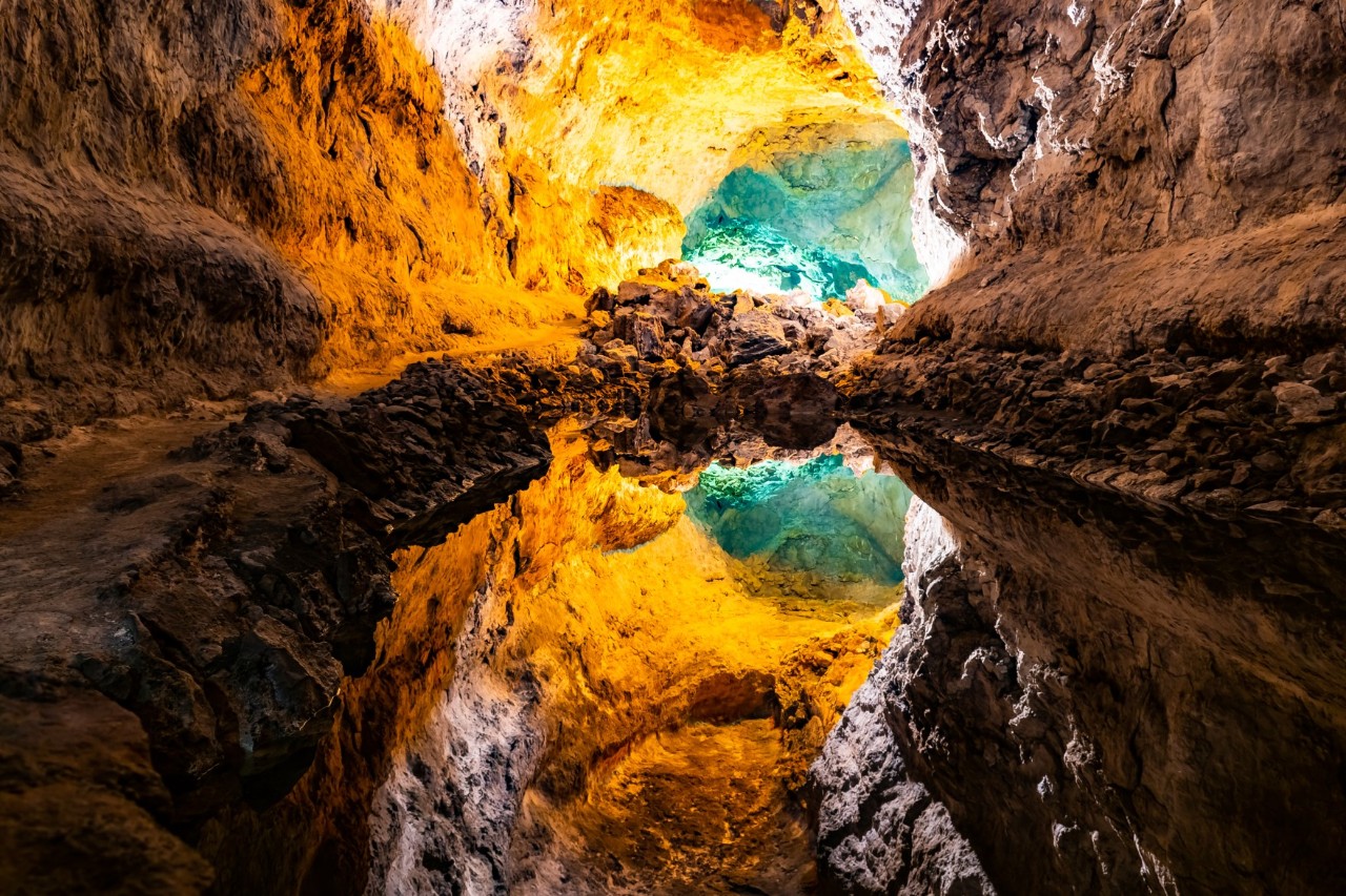Innenansicht der Cueva de los Verdes mit beleuchteten Felswänden und Wasserfläche.