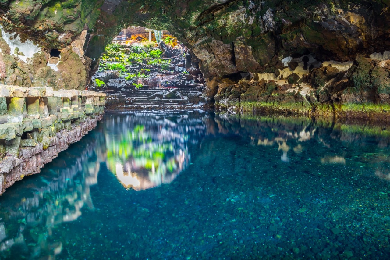 Lava-Grotte mit natürlichem Wasserbecken und üppiger Bepflanzung auf Lanzarote.