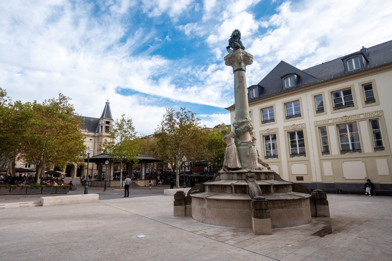Eine Fußgängerzone mit dem Place d'Armes, einer Statue und Häusern.
