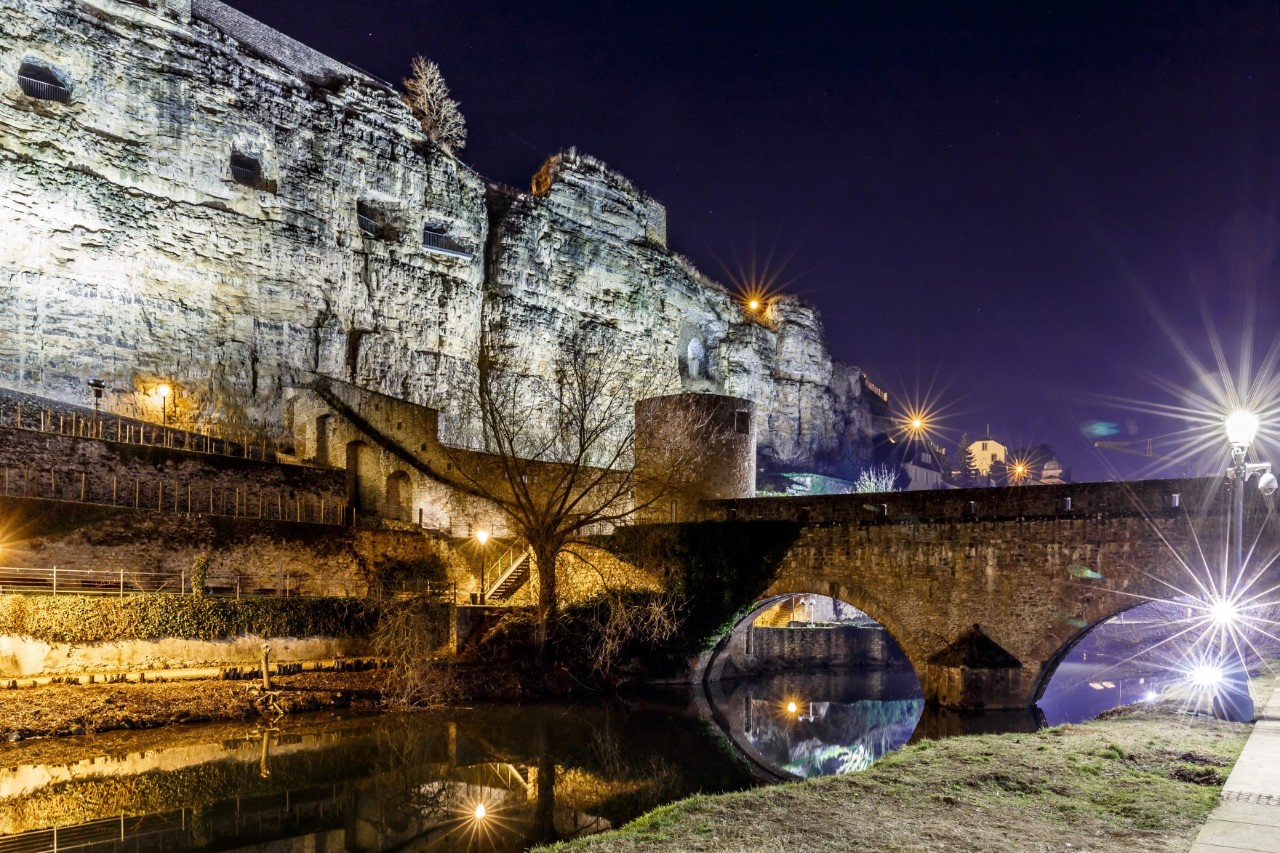 Eine Festung und eine Steinbrücke am Fluss in der Dunkelheit.
