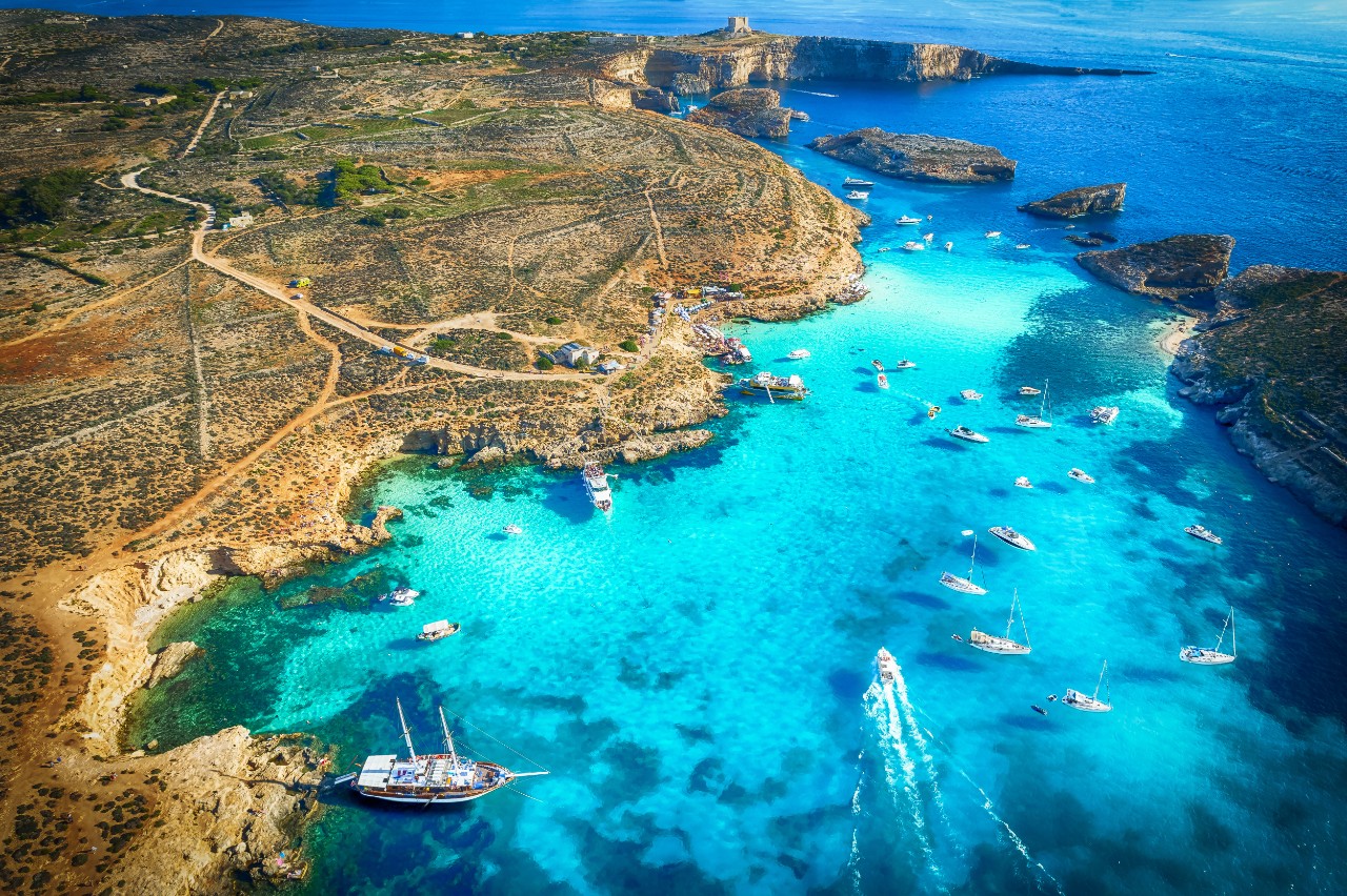 Luftbild der Blauen Lagune auf Comino mit türkisblauem Wasser und Booten.