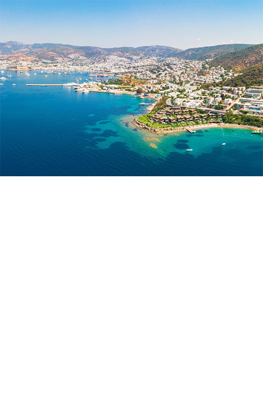 Luftbild von der Küste bei Bodrum mit blauem Meer und grüner Hügellandschaft.