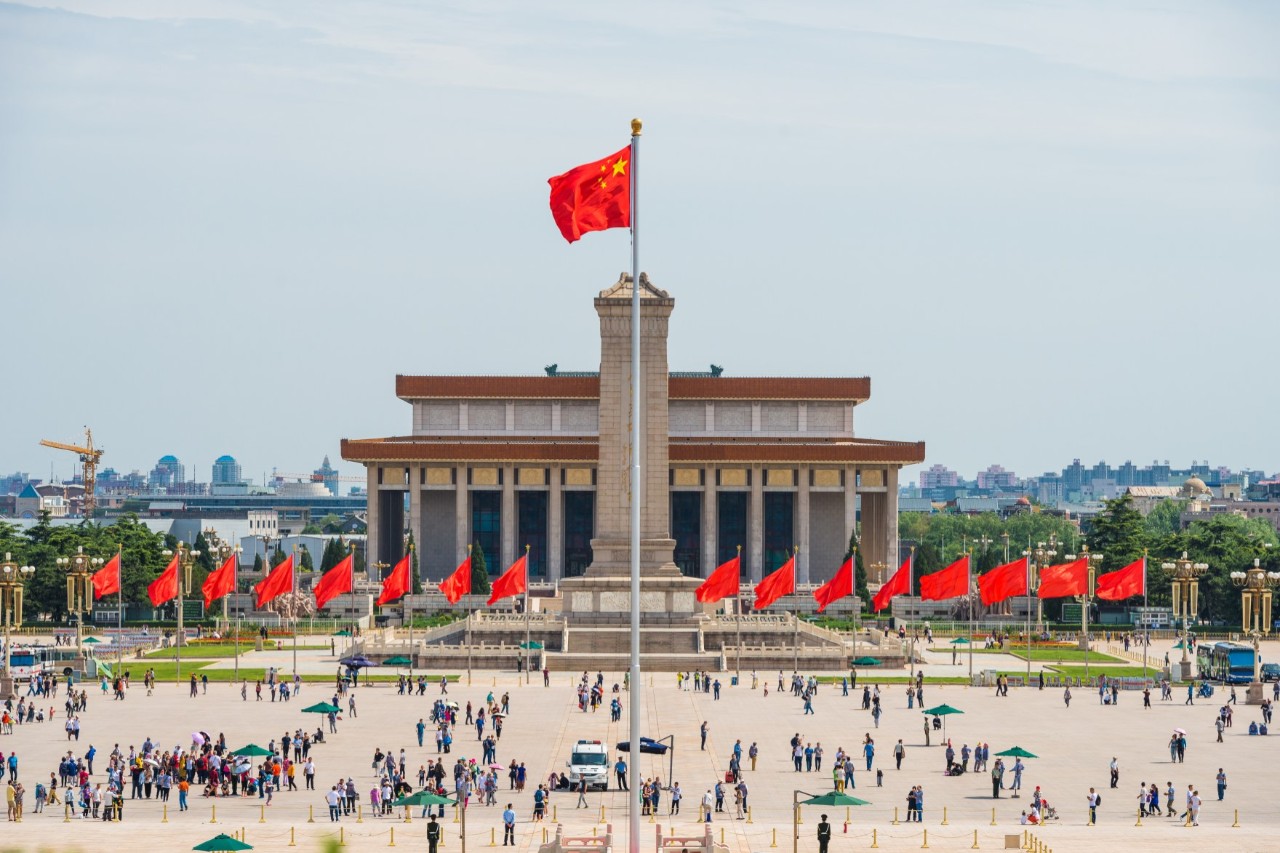Weitläufiger Tian’anmen-Platz mit Besuchergruppen und Flaggenmast.