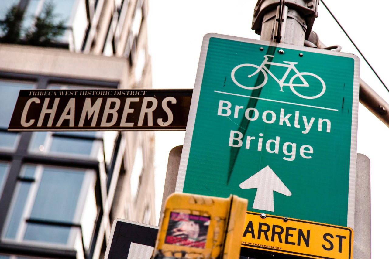 Schild der Brooklyn Bridge vor der Skyline von Manhattan.