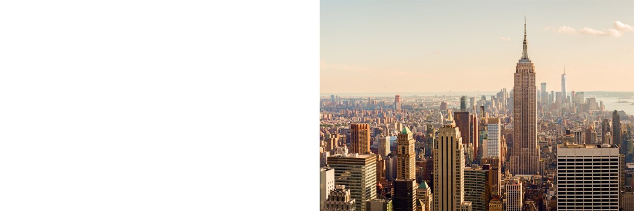 Skyline von New York City im warmen Abendlicht mit leuchtenden Gebäuden.
