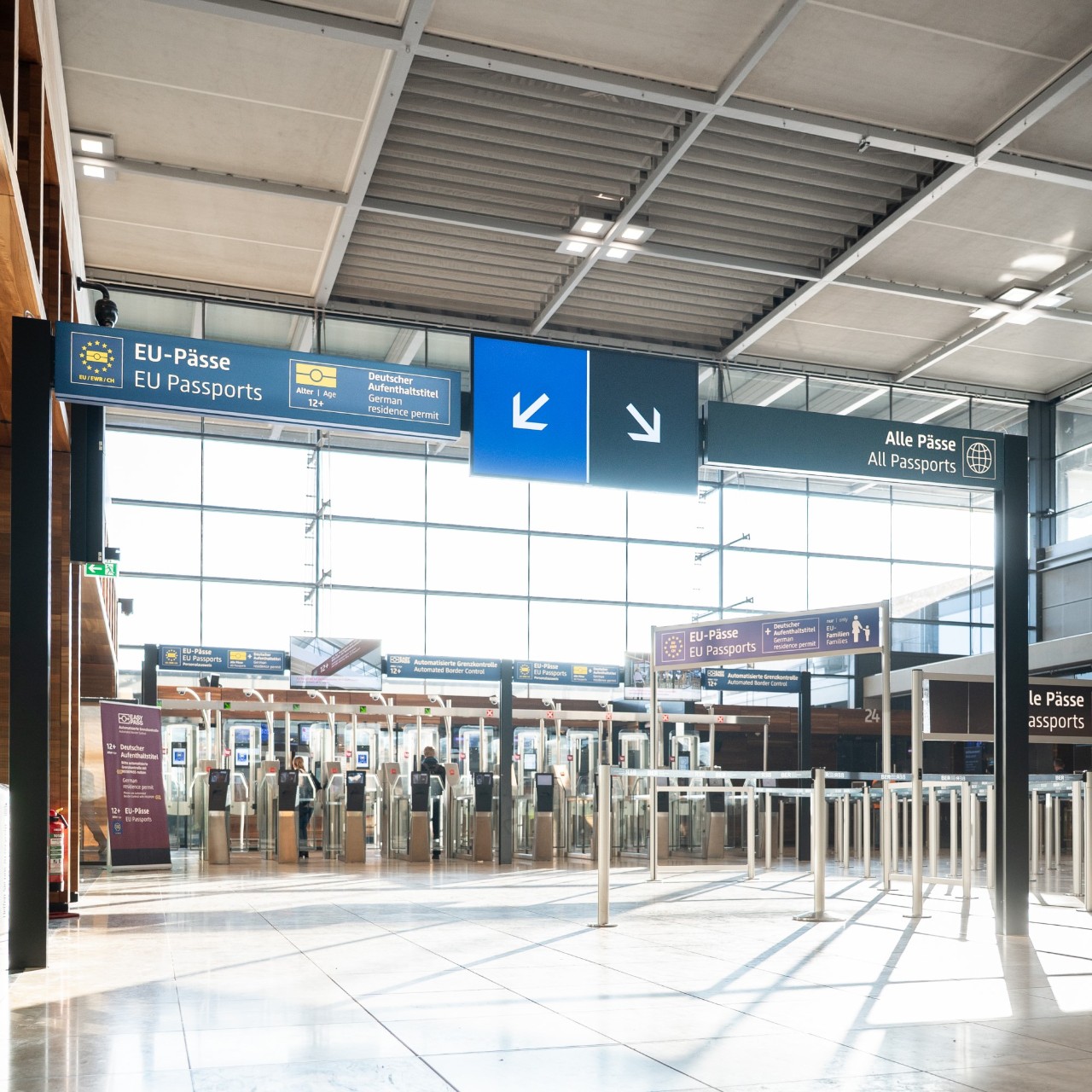 Blick auf graune und blau codierte Schilder und Monitore in der Ausreise. 