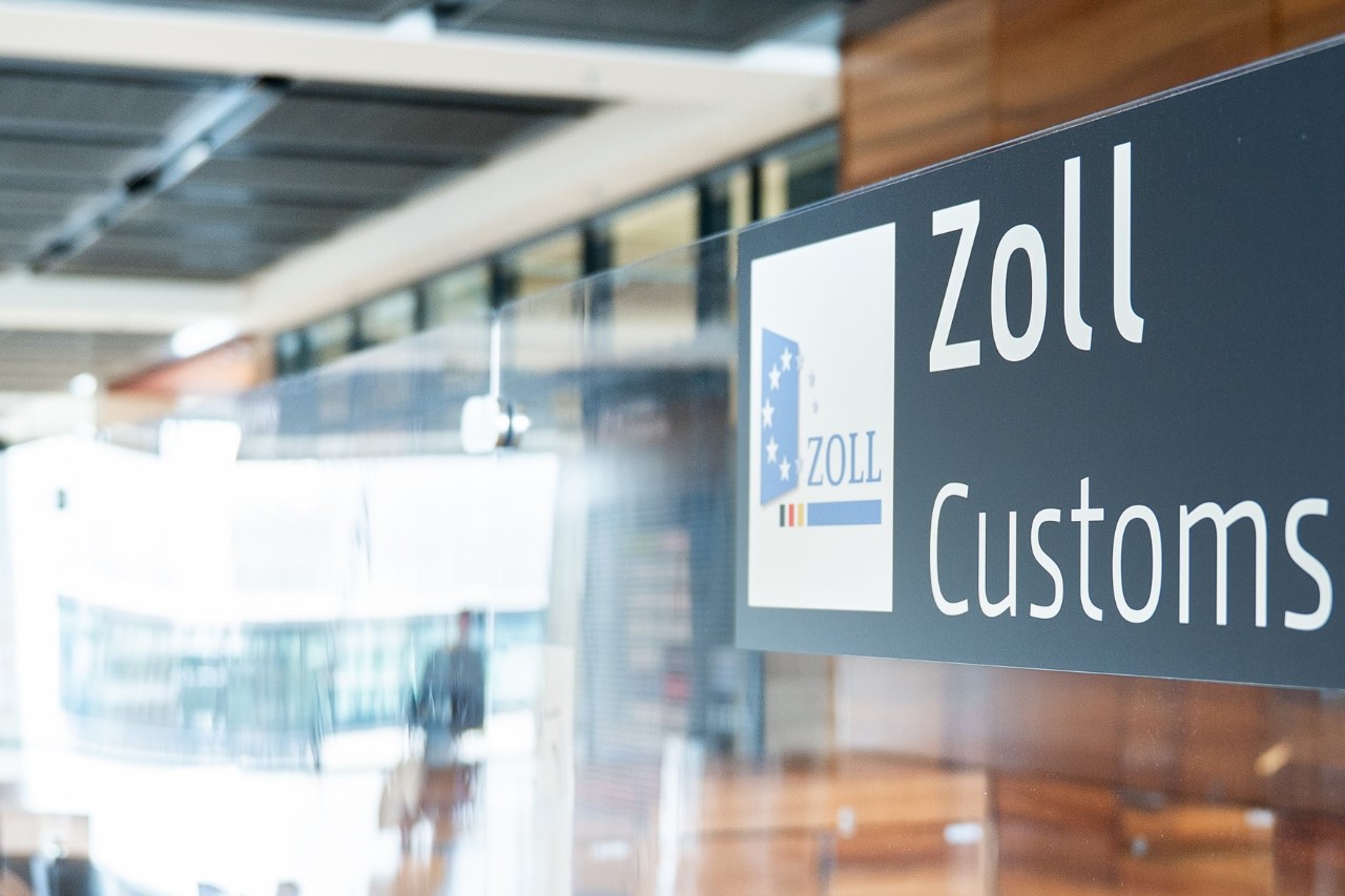 Schild mit dem Aufdruck "Zoll, Customs". Hintergrund ist verschwommen.