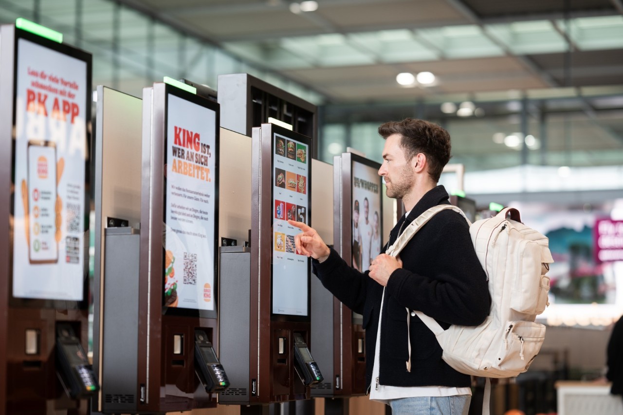 Eine Person bestellt Essen am Self Service Automaten