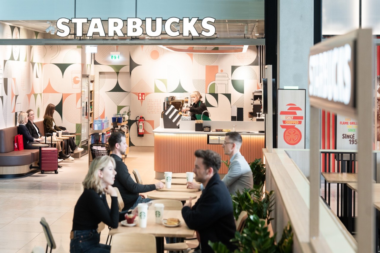 2 Personen sitzen bei Starbucks im Hintergrund Personen in der Filiale