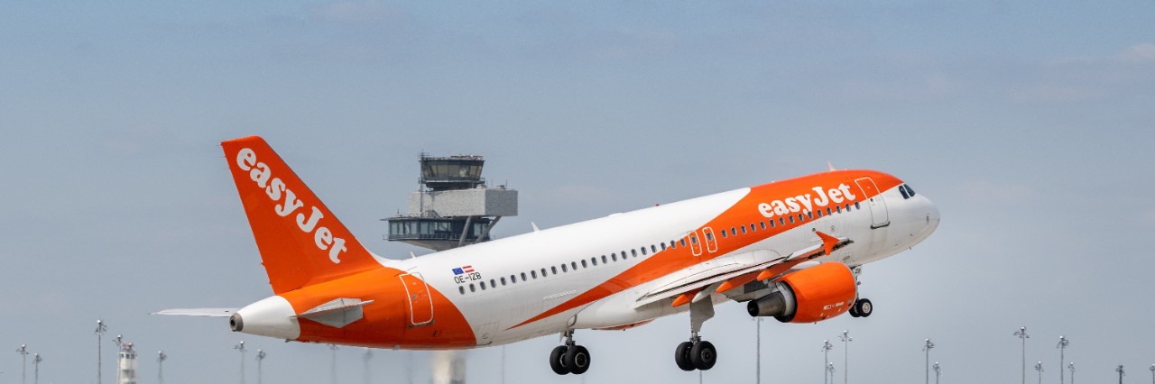 Ein easyJet-Flugzeug kurz nach dem Start. Im Hintergrund ist der Tower des BER zu sehen.