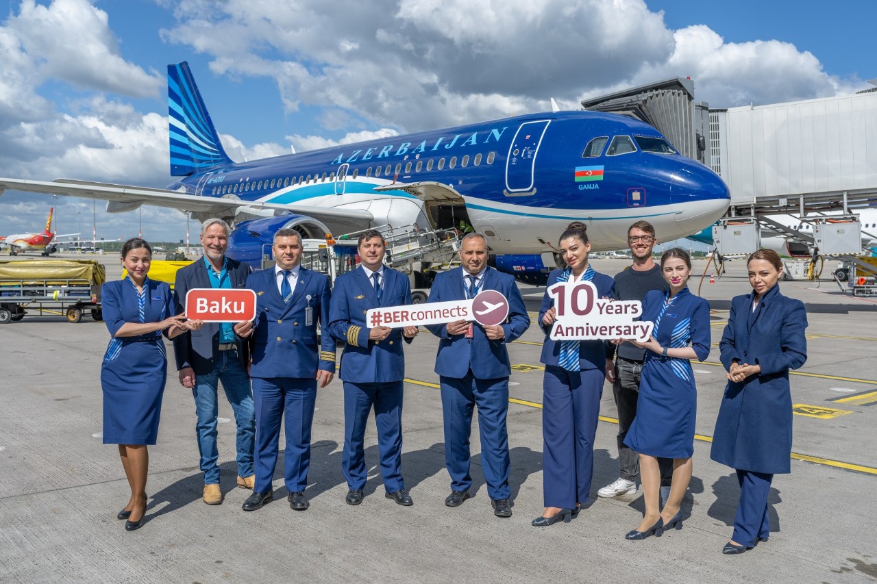 Ein Gruppe Menschen vor eine Flugzeug von Azerbaijan Airlines. Sie halten Schilder in die Höhe.