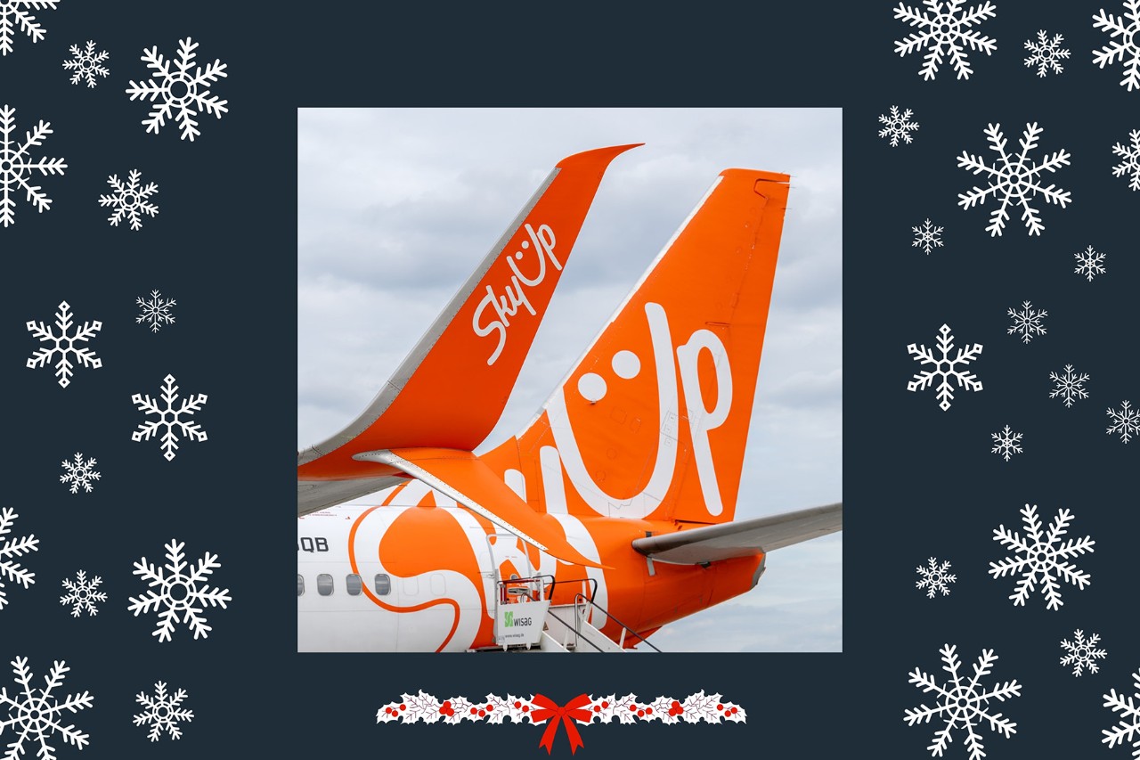 Heck eines SkyUp Flugzeugs auf dunklem Hintergrund mit Schneeflocken und Weihnachtsdeko