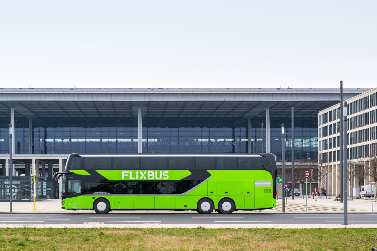 Ein grüner Fernbus steht vor dem Terminal. Der Fernbus ist von der Seite zu sehen.